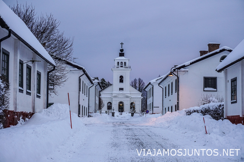 Calle nevada con iglesia blanca al fondo en Suecia