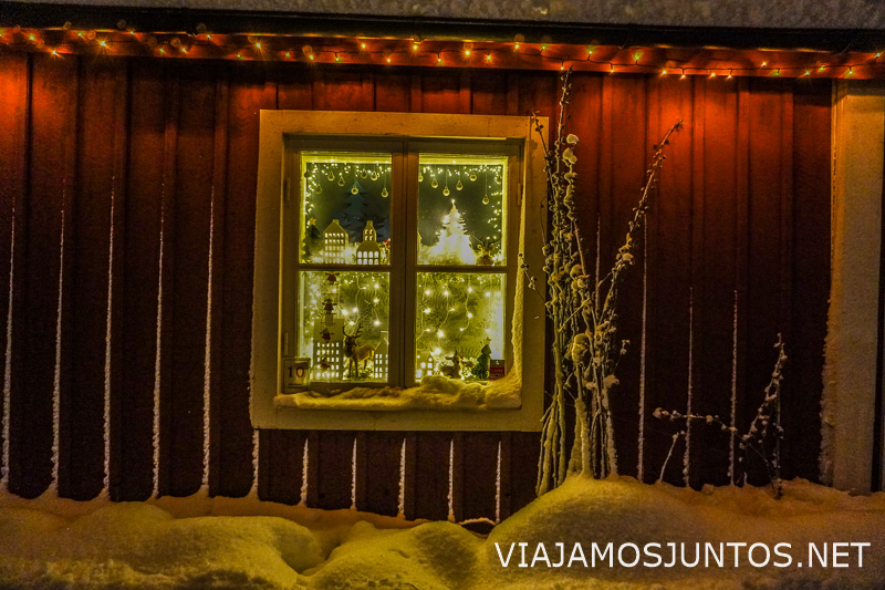 Ventana iluminada en una casa de madera durante el invierno en Suecia